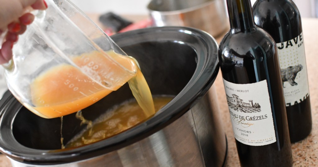 pouring mulled wine in a slow cooker