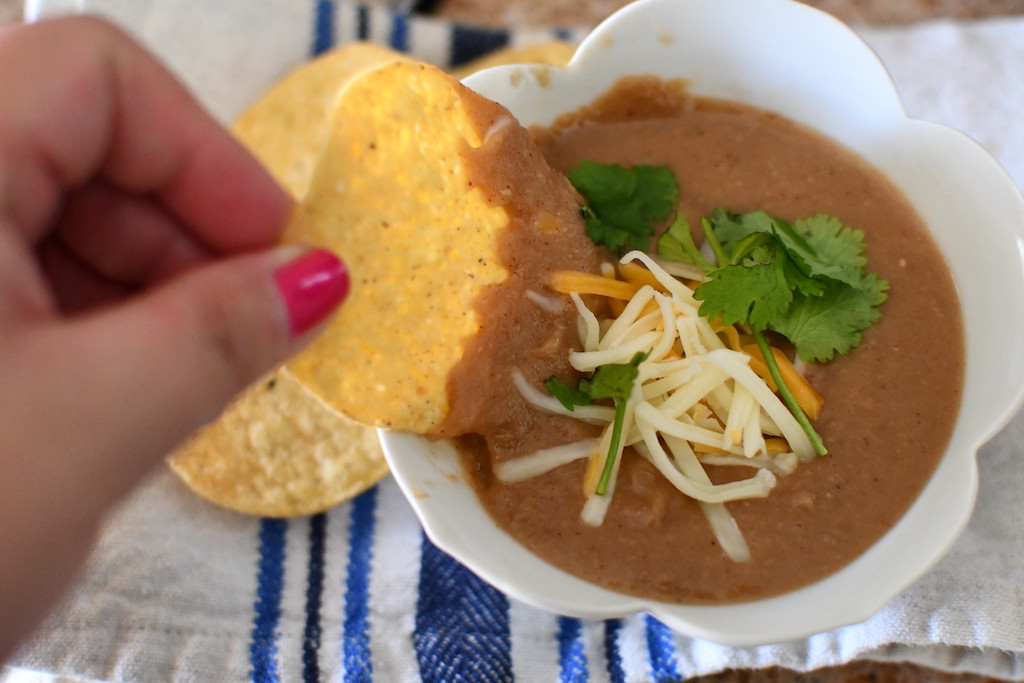 dipping tortilla chip in refried beans 