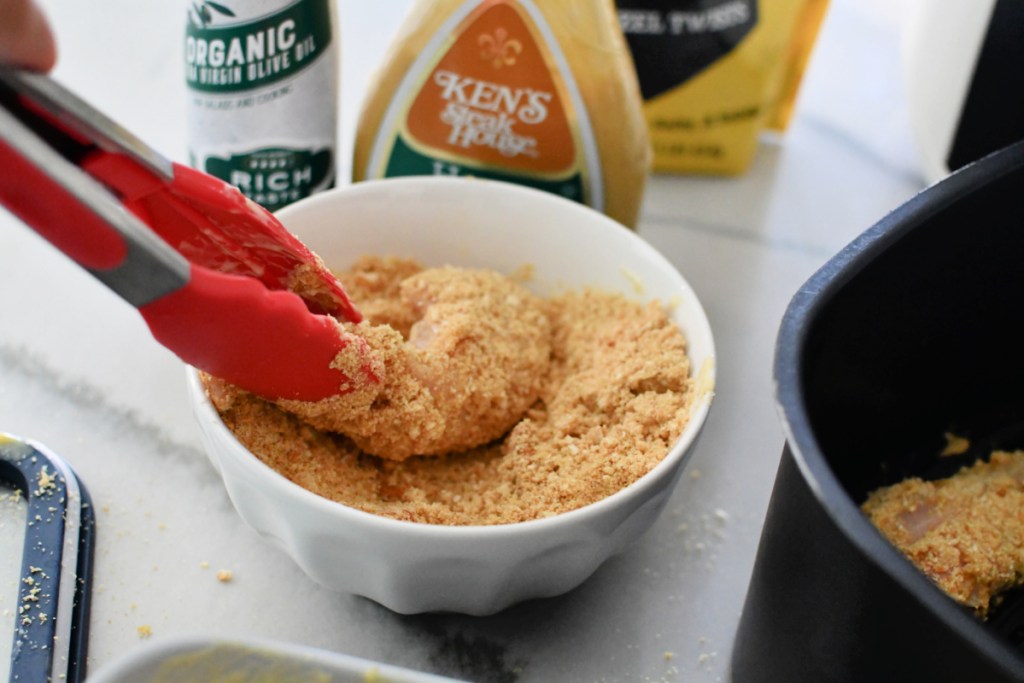 adding pretzel breading to chicken before cooking 