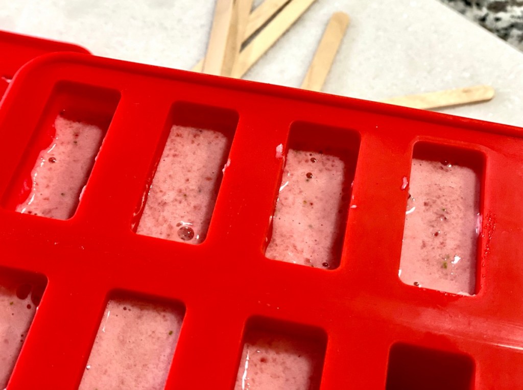 red popsicle mold with melted popsicle ingredients