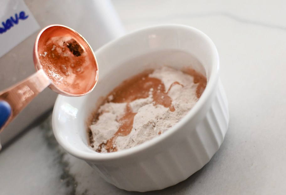 adding cake mix and water to a mug cake