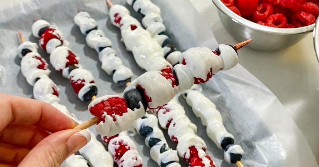 hand holding yogurt-dipped berries on a stick