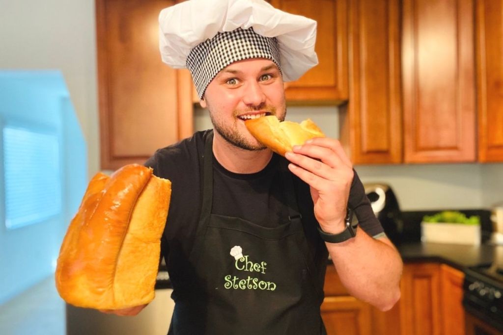 A man holding a loaf of bread and eating some