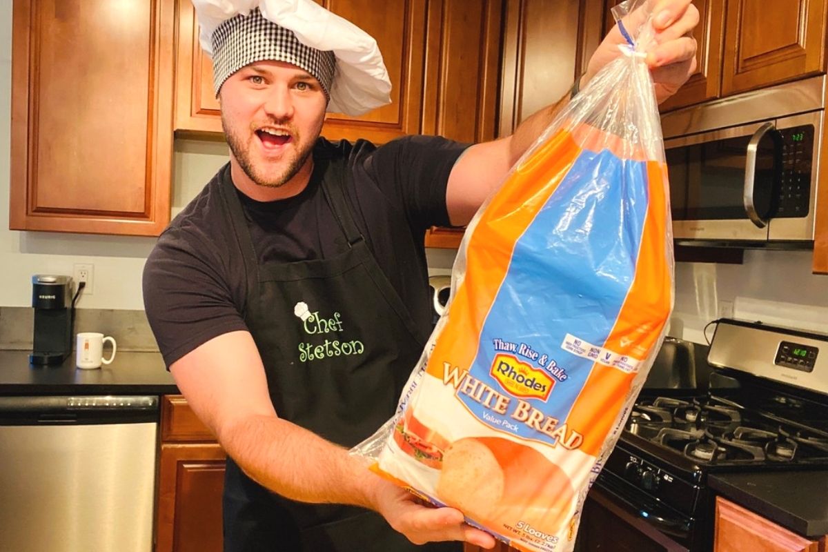 A man wearing a chef hat holding a loaf of frozen bread dough in a bag