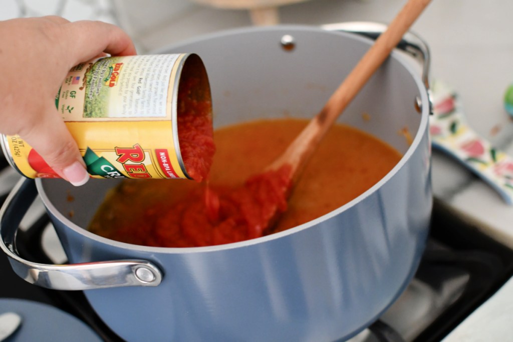 adding crushed tomatoes to lasagna soup