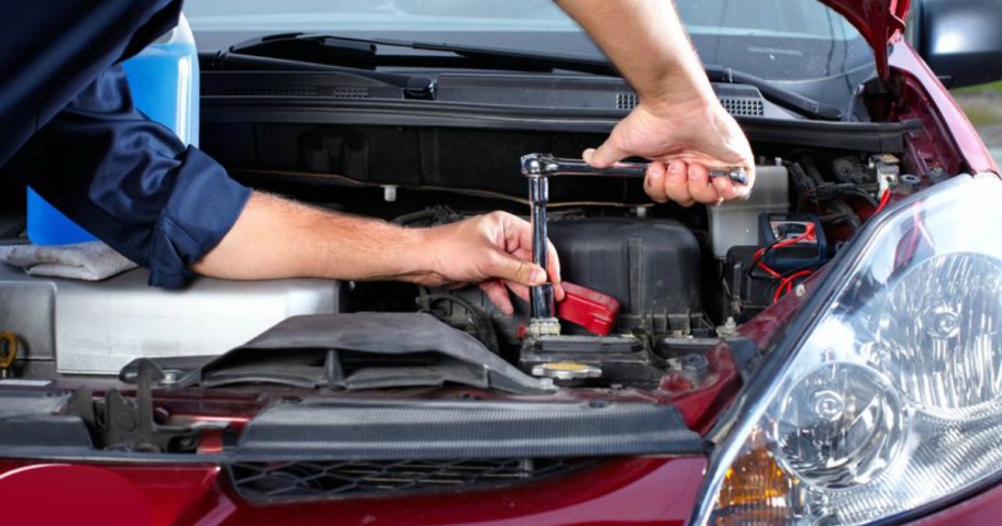 person turning wrench in car engine