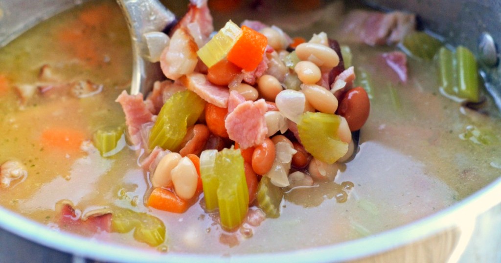 spooning ham and bean soup from pot