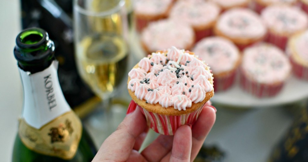 woman holding a pink champagne cupcake