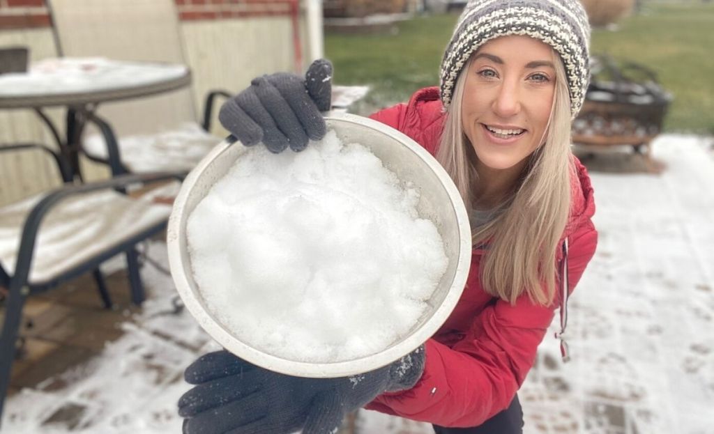 A woman holding a bowl of snow outside