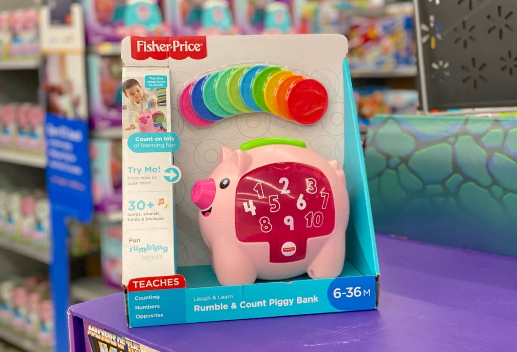 toy pink piggy bank sitting on purple shelf 