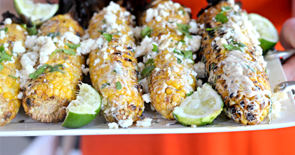 holding a tray of mexican grilled corn 