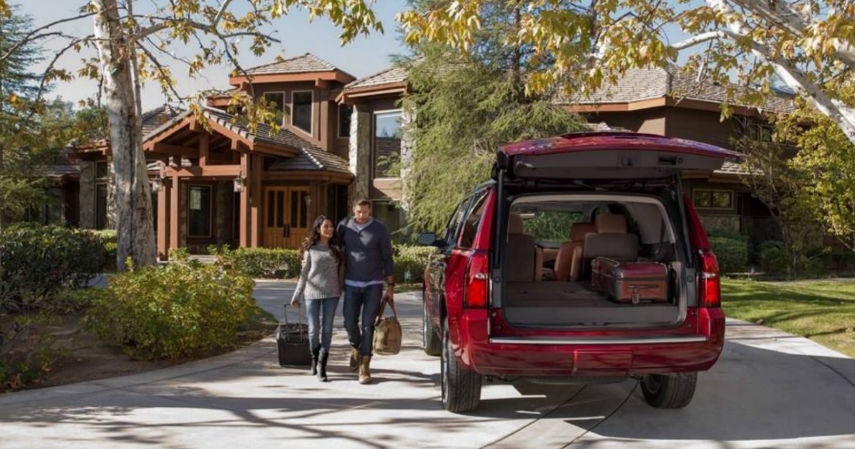 red car sitting outside of log cabin with open trunk