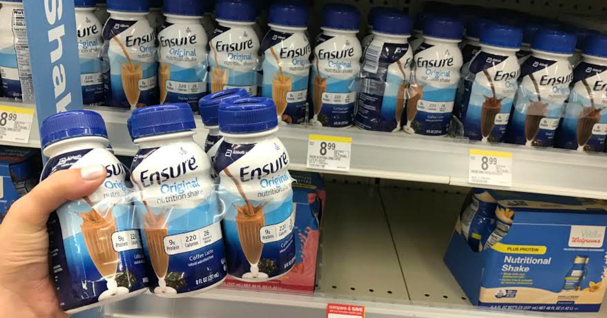 hand holding a pack of ensure beverages in front of a store display shelf