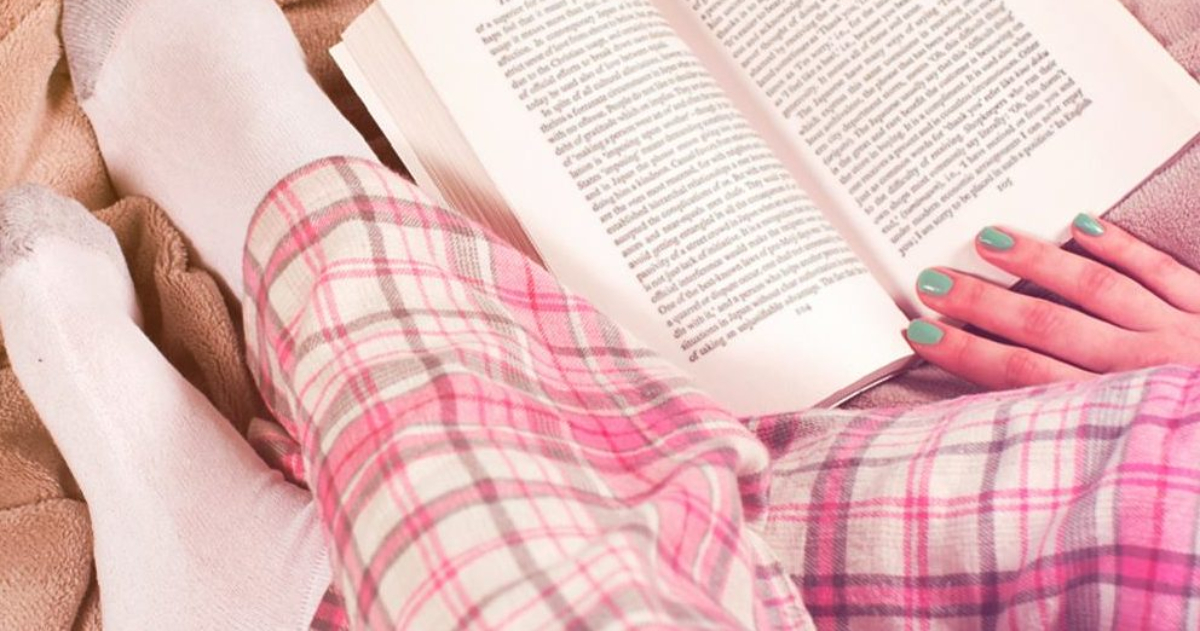 painted fingernails holding a book with pajama pants and white socks
