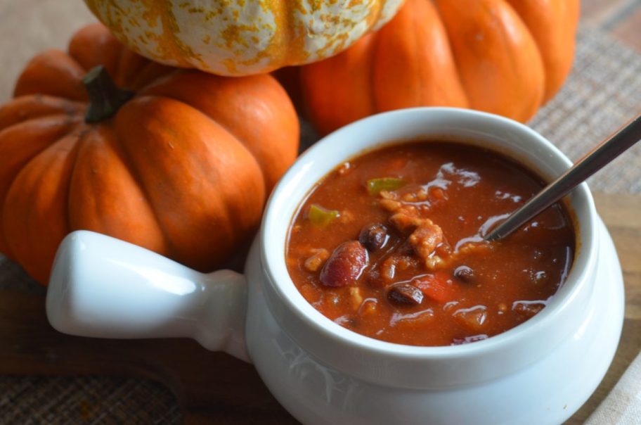 bowl of pumpkin chili next to mini pumpkins 