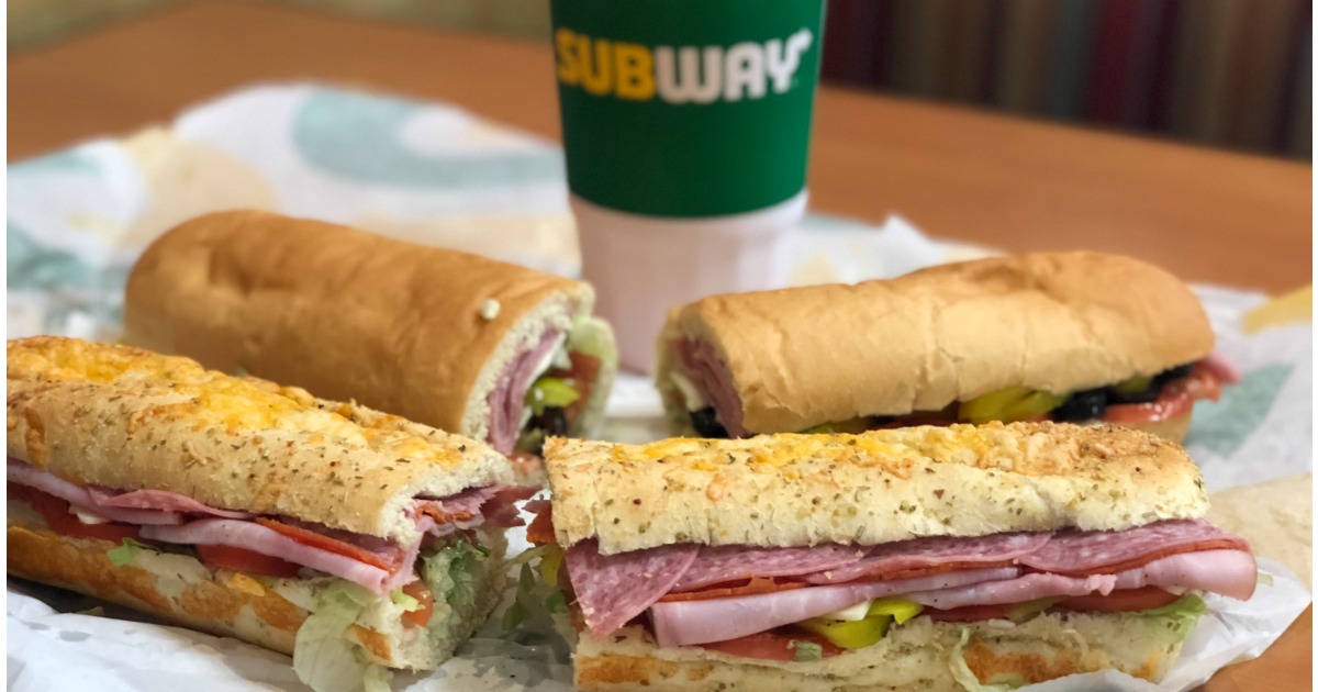 two subway sandwiches in front of subway cup