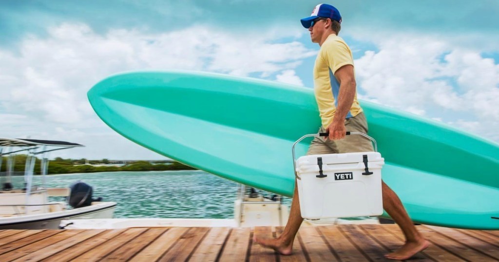 man carrying cooler and surf board