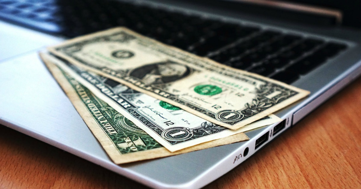 dollar bills on an open laptop