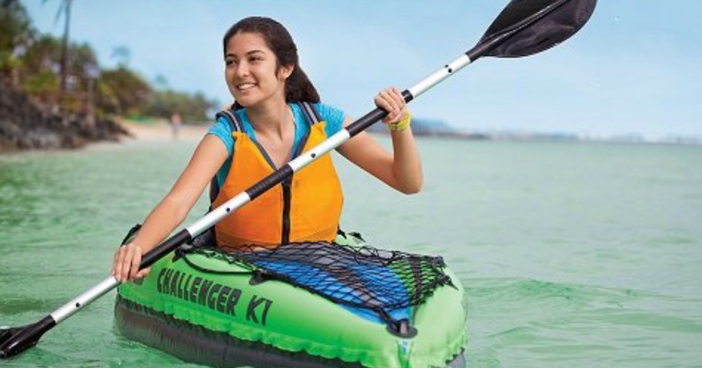 person in green kayak on lake smiling