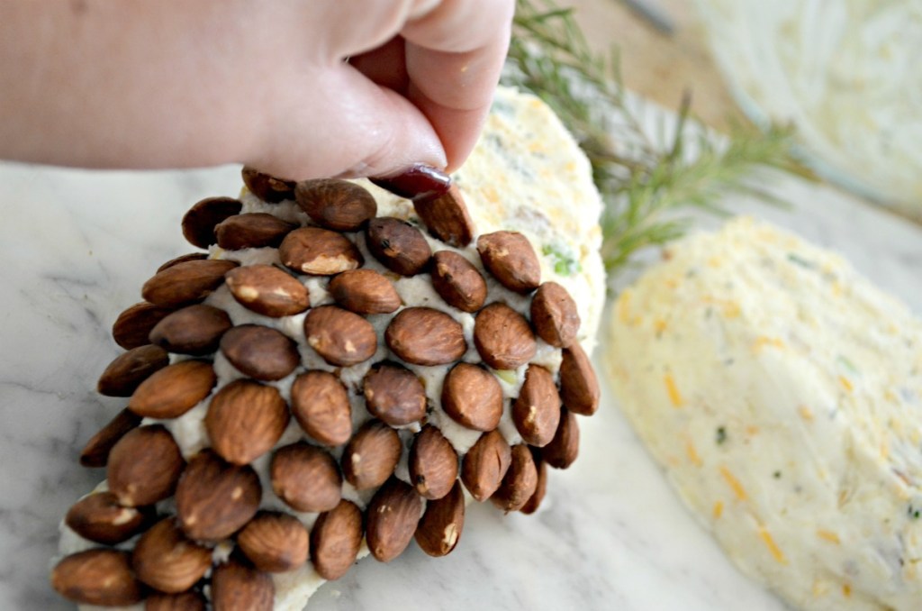 putting almonds on a pinecone cheeseball