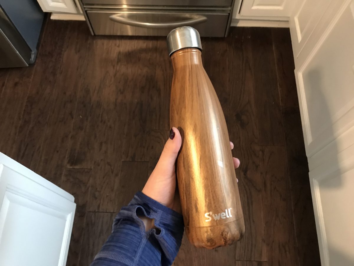 hand holding a brown swell bottle in kitchen