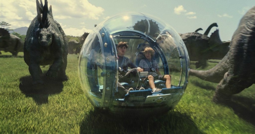 Jurassic World scene of kids riding glass ball ride and dinosaurs in background