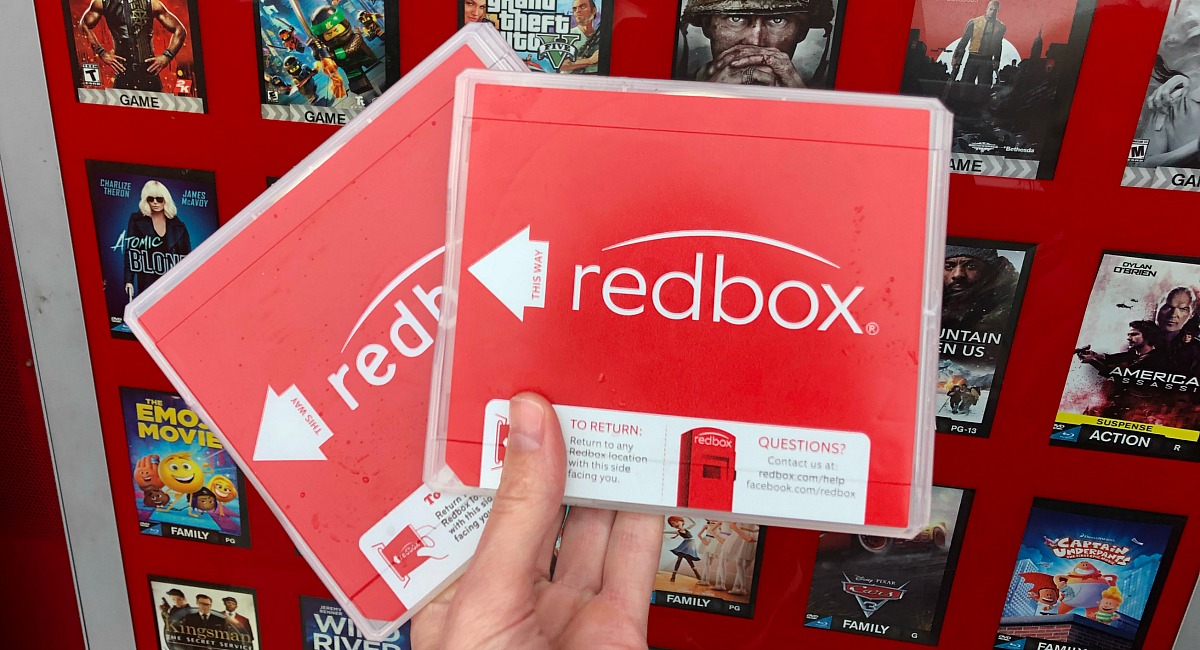 a hand holding two Redbox movie cases outside of the Redbox kiosk - birthday freebies
