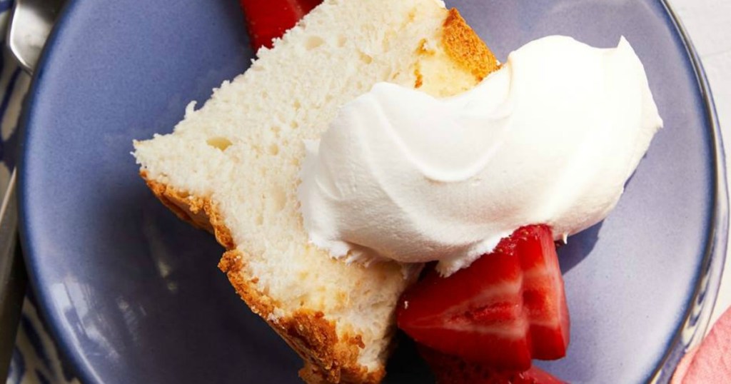 angel food cake slice on plate with whipped cream and strawberries