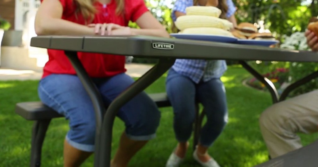 family sitting outside on picnic table 