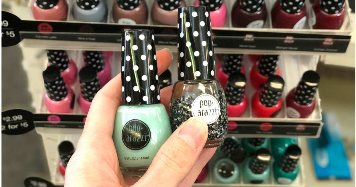 hand holding two bottles of nail polish in front of a display rack in cvs