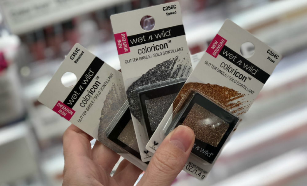 Hand fanning out three Wet n Wild Eye Shadows