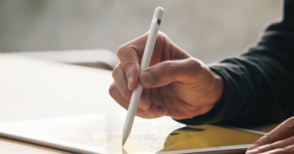 Hand using an Apple Pencil to write on a tablet