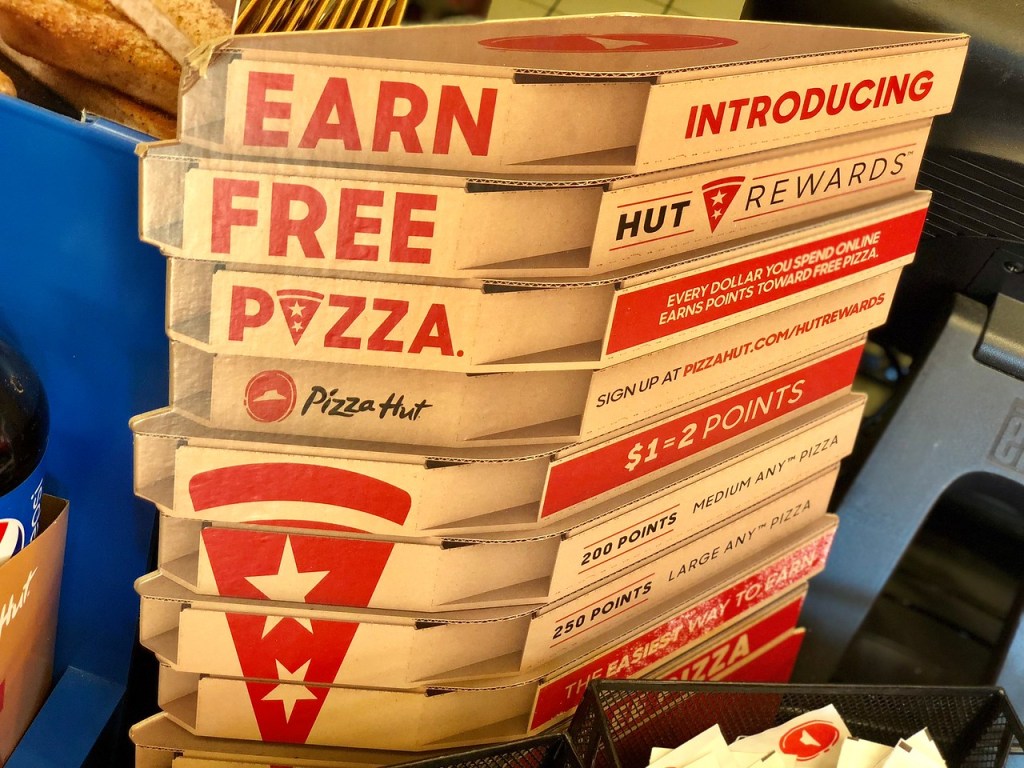 Stack of pizza hut boxes with wording on the side of boxes that says earn free pizza