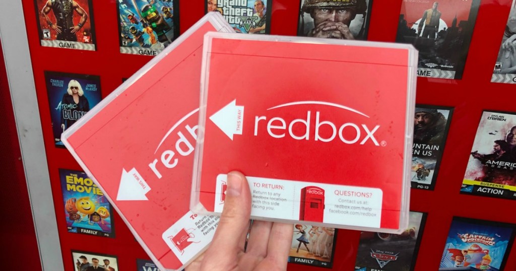 person holding two redbox dvds