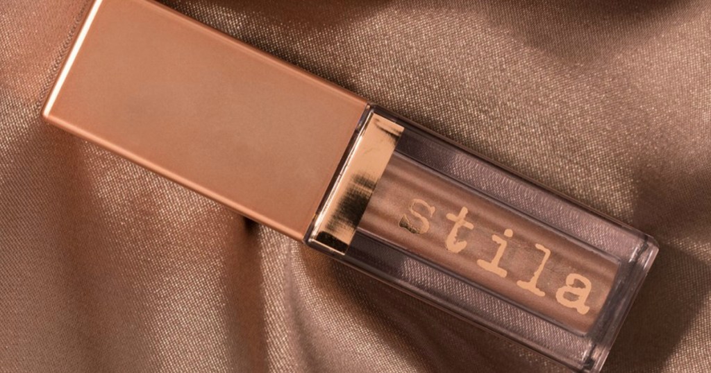 bottle of Stila Shimmer & Glow on a brown shiny fabric background