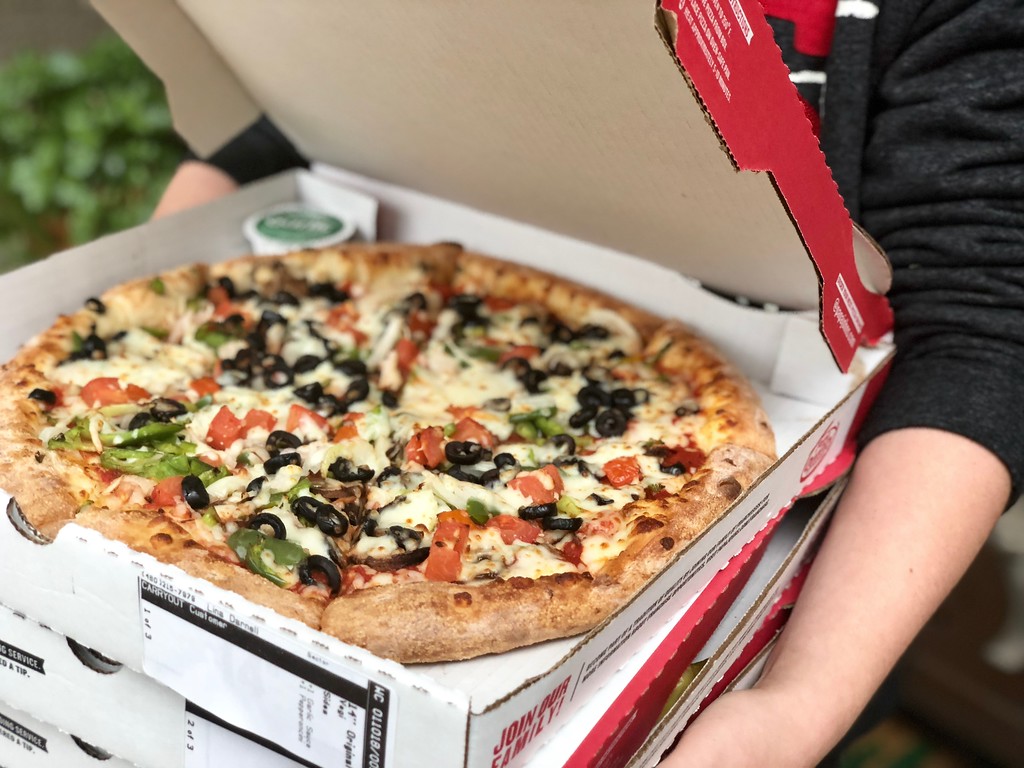 Person carrying multiple boxes of Papa John's pizzas