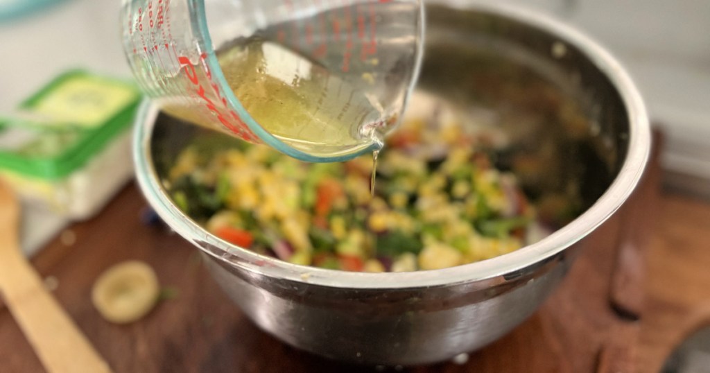 adding dressing to corn salad