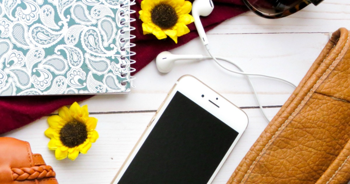 an iPhone and earbuds on a rustic table