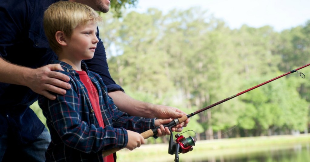 man helping boy with fishing pole