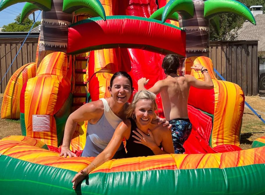 two women on bounce house waterslide