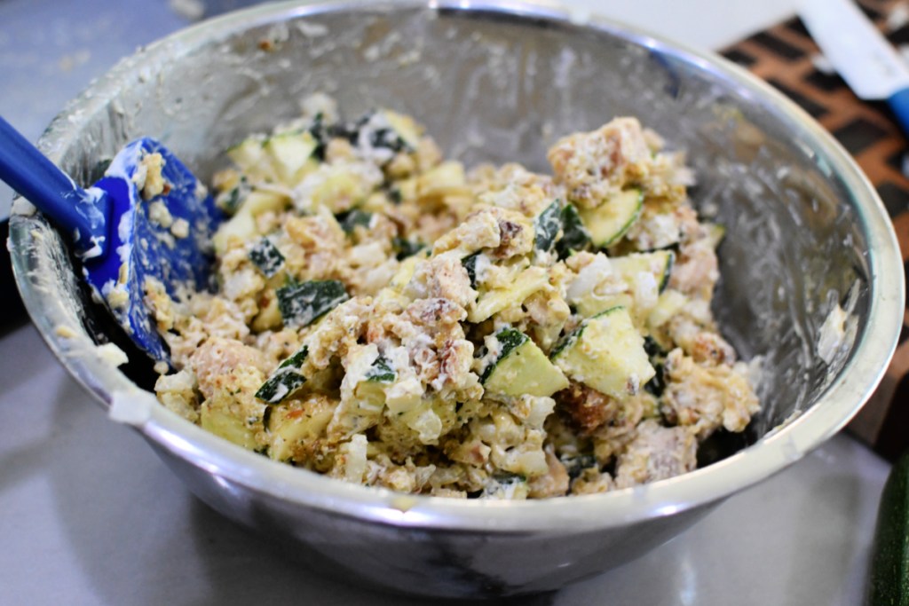 mixing chicken and zucchini casserole together in a large mixing bowl