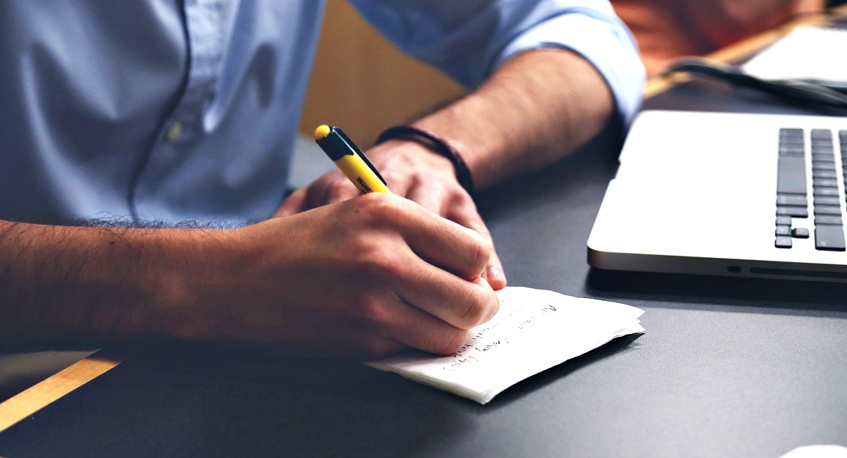 hand writing notes on a slip of paper