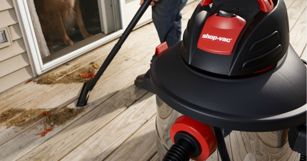 man using a shop vac to suck up debris on deck