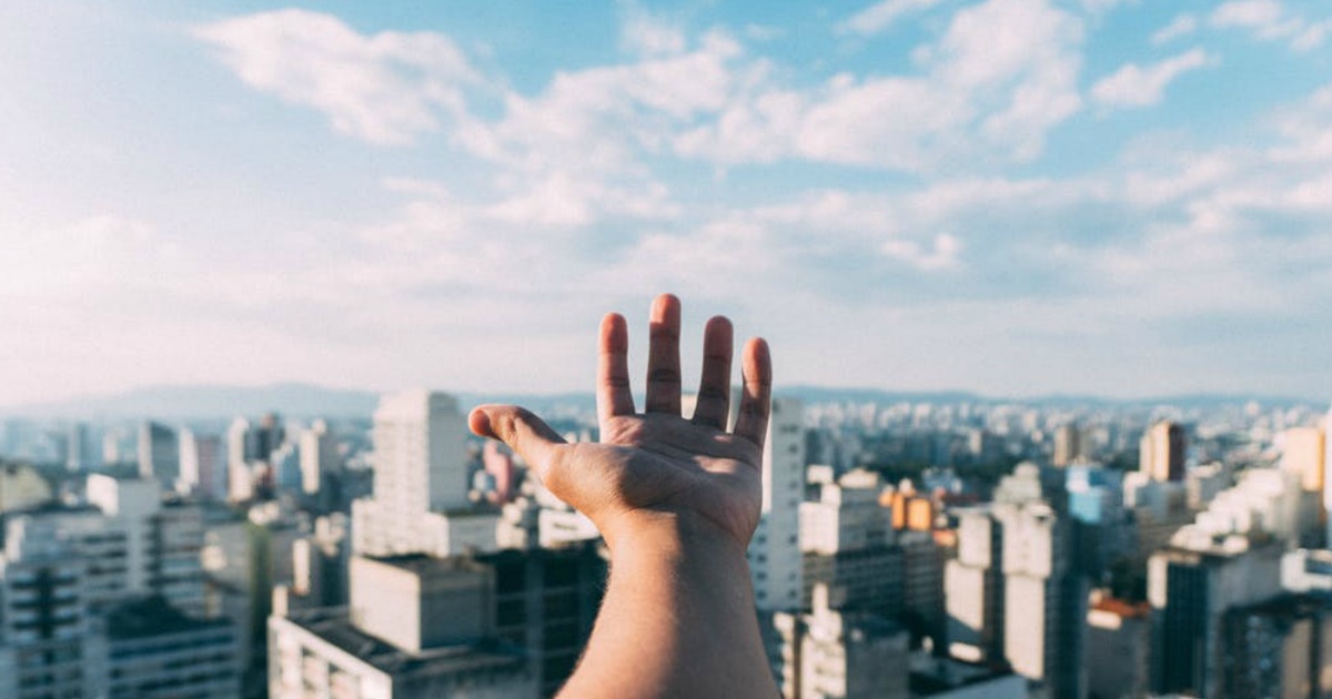 hand reaching out over city skyline