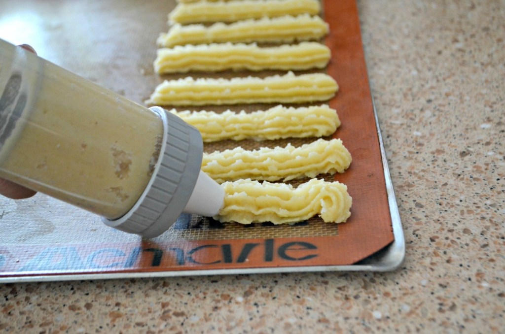 piping out churros onto baking sheet before air frying