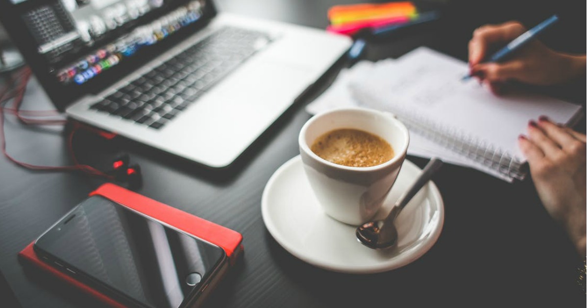 cup of coffee next to a laptop