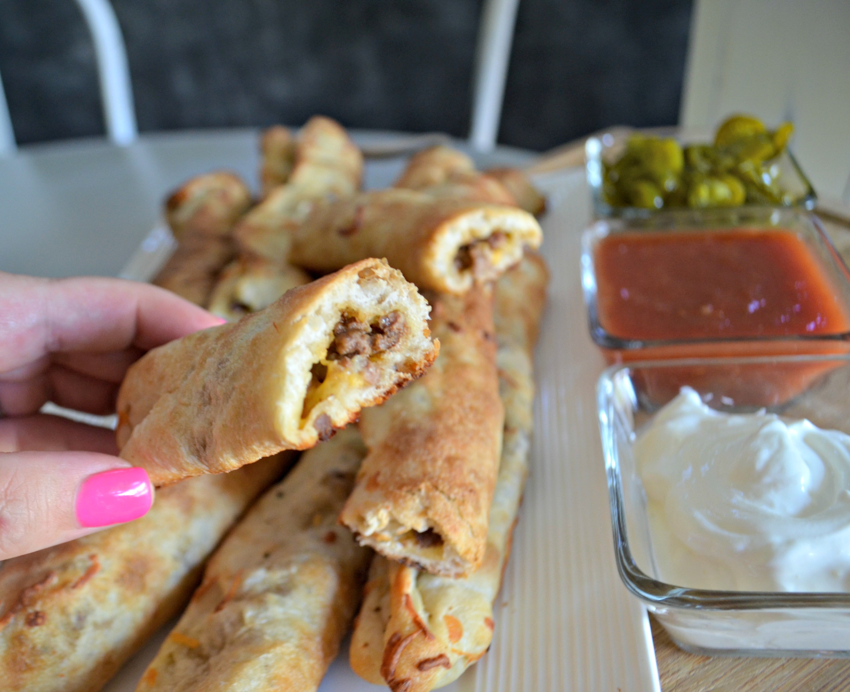Easy 3 Ingredient Cheesy Taco Stuffed Breadsticks -after baking with the center showing from the end plus dipping sauces