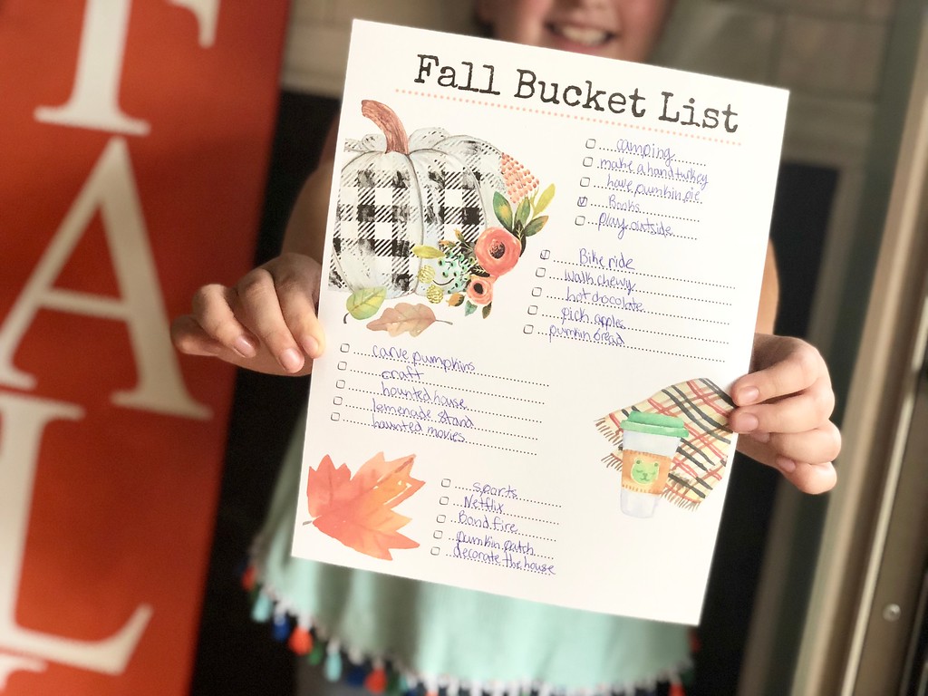 Our free printable fall bucket list filled out and held by a young girl