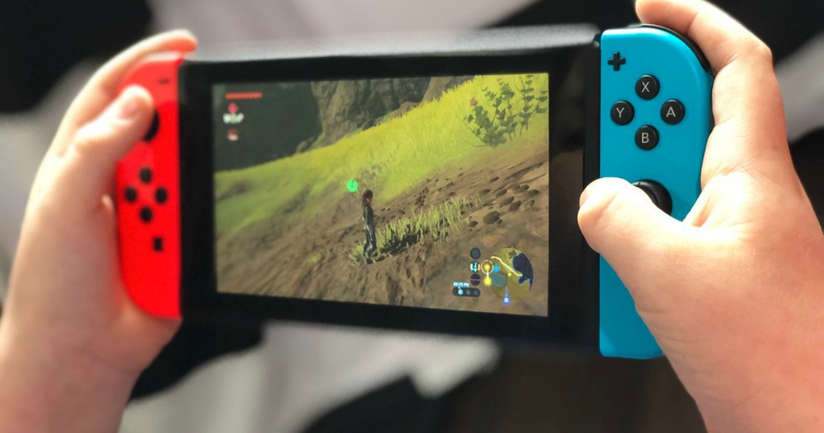 person holding nintendo switch console with red and blue joycons