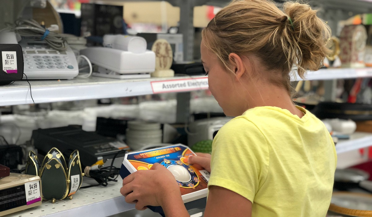 collin's deals and finds this week — piper looking at products on shelf at the thrift store